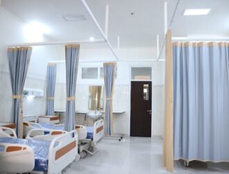 hospital beds arranged side by side separated by curtains