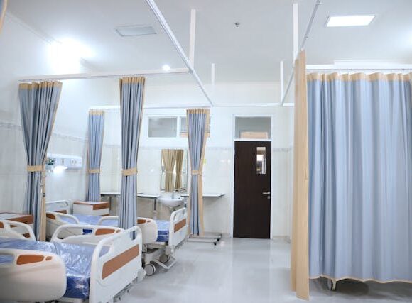 hospital beds arranged side by side separated by curtains