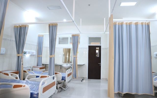 hospital beds arranged side by side separated by curtains