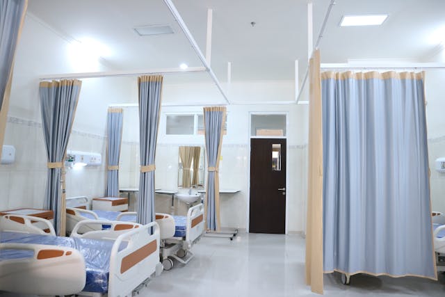 hospital beds arranged side by side separated by curtains